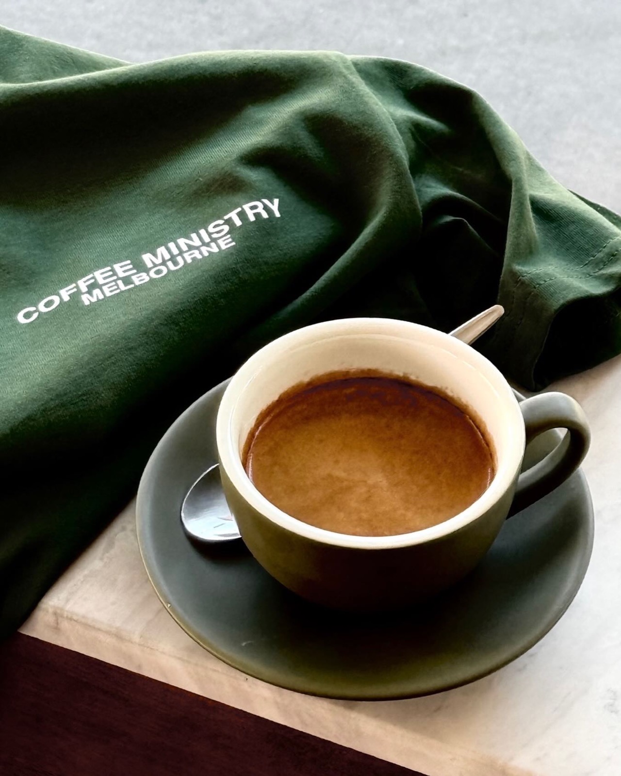 Coffee Ministry branded apron beside an espresso