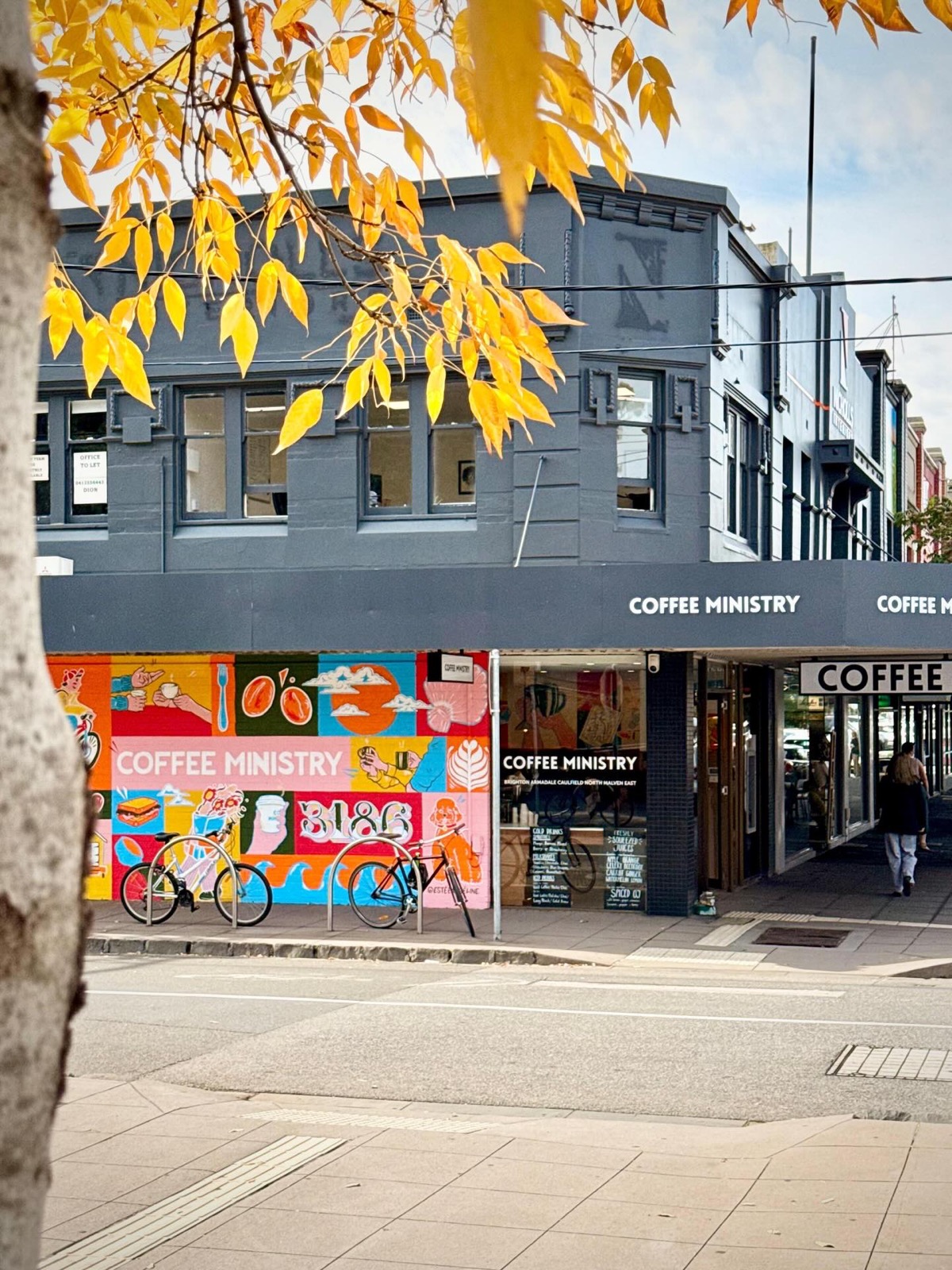 Coffee Ministry storefront and mural under autumn leaves